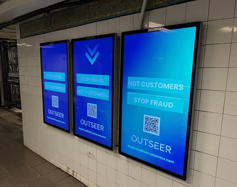 Three Outseer campaign screens installed side by side in a transit corridor.